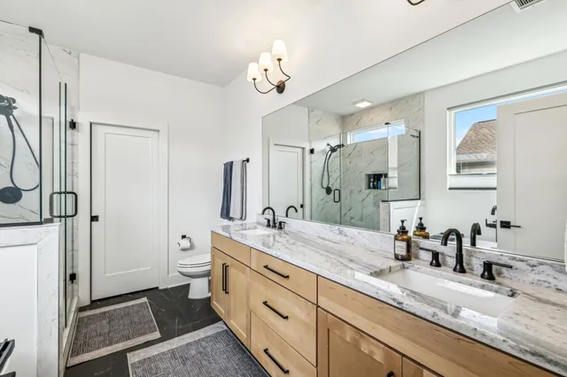 a spacious bathroom with a granite countertop sink a mirror and a shower