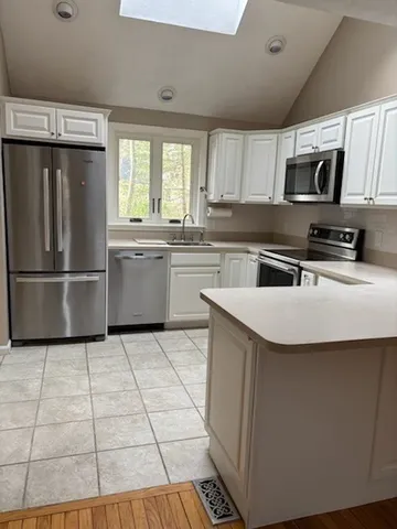 a kitchen with stainless steel appliances a sink a stove a refrigerator cabinets and a window
