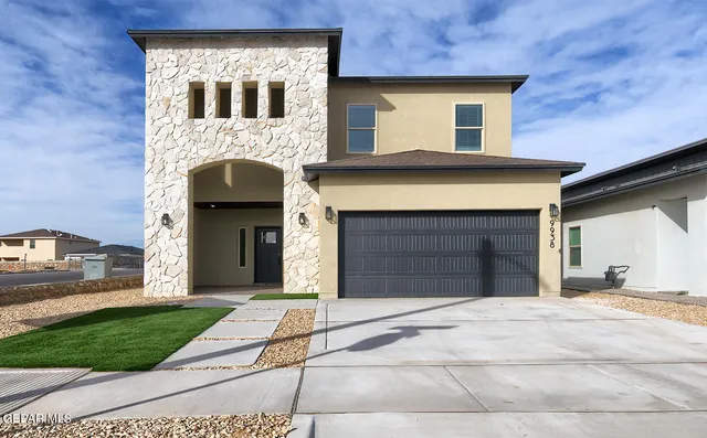 a front view of a house with yard and garage