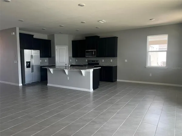 a view of kitchen with stainless steel appliances granite countertop a stove top oven a sink and a refrigerator