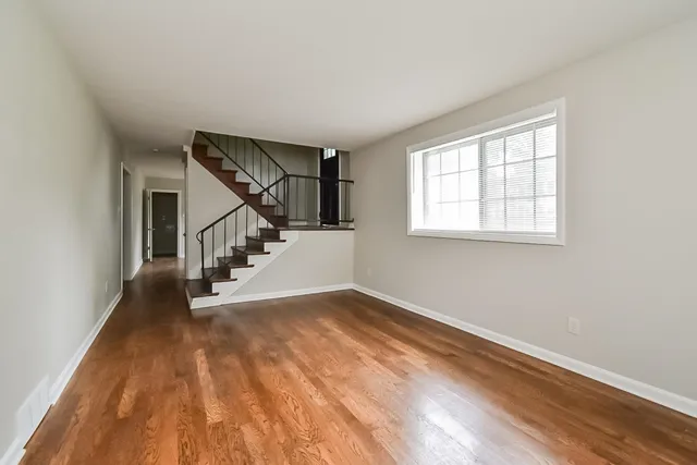 a view of an empty room with wooden floor and stairs