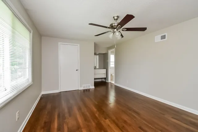 a view of empty room with wooden floor and fan