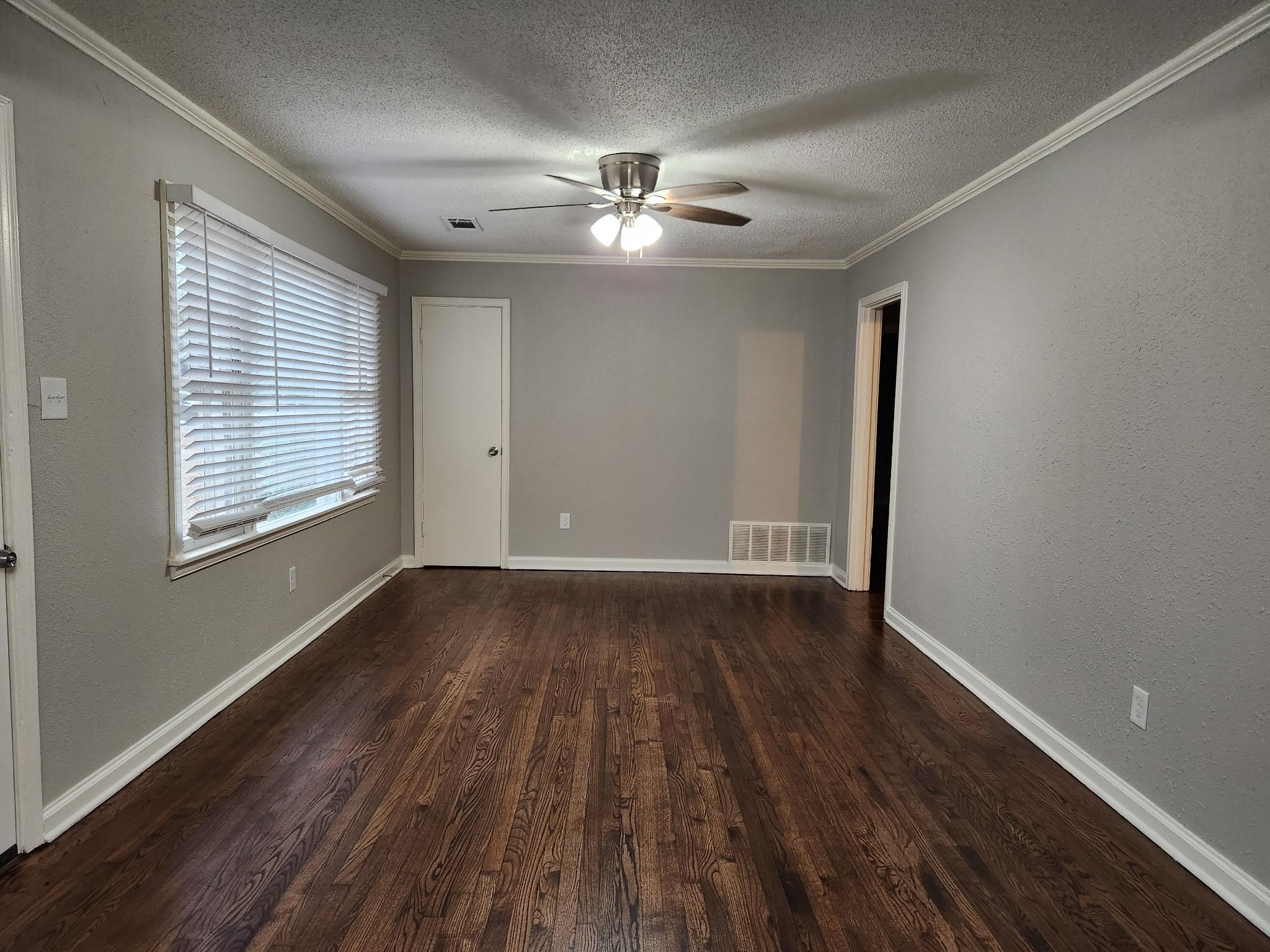 866 Colonial Road Memphis, TN 38117 - Photo 6 of 15 Empty room featuring dark wood-type flooring, a textured ceiling, ornamental molding, a ceiling fan, and a textured wall