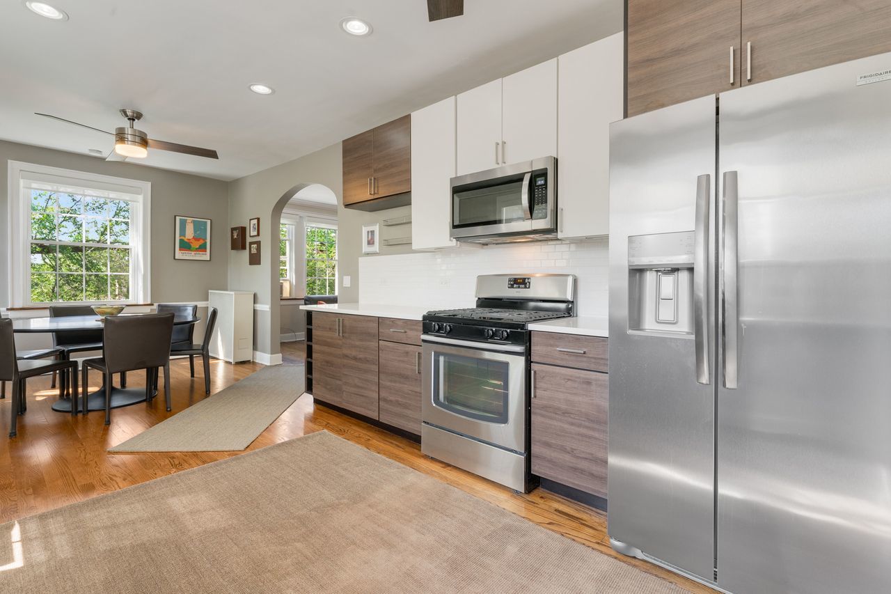 1217 Hull Terrace, Unit 3A Evanston, IL 60202 - Photo 14 of 28 a kitchen with stainless steel appliances kitchen island granite countertop a refrigerator a stove a sink dishwasher a dining table and chairs with wooden floor