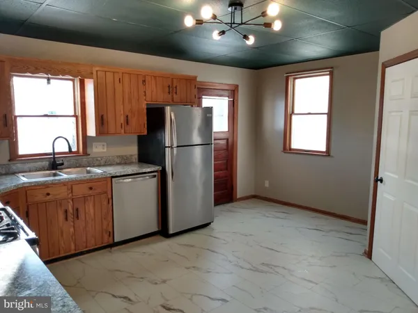 a kitchen with refrigerator a sink cabinets and wooden floor