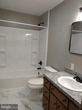 a bathroom with a granite countertop sink toilet a mirror and shower