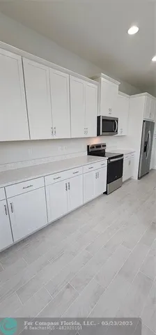 a kitchen with stainless steel appliances granite countertop a stove a sink and white cabinets