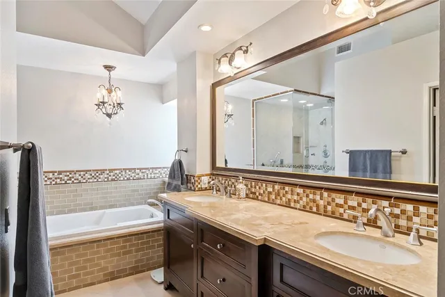 a bathroom with a granite countertop sink a large mirror and a bathtub