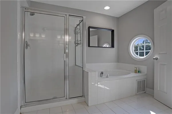 a spacious bathroom with a tub shower and mirror
