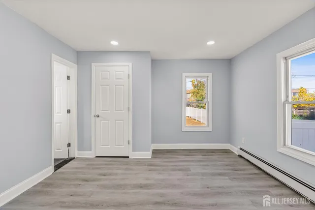 a view of an empty room with window and wooden floor