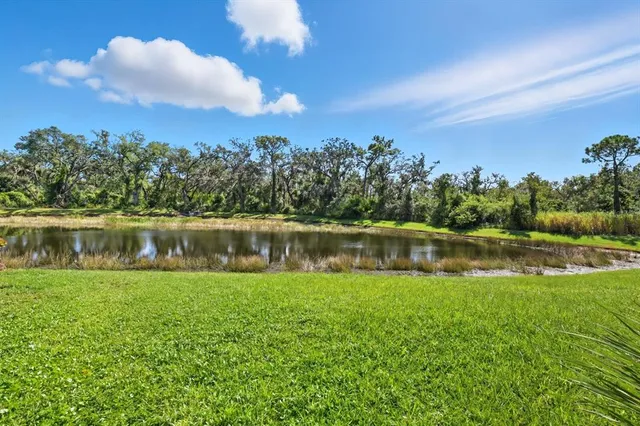 a view of a lake with a yard and large trees