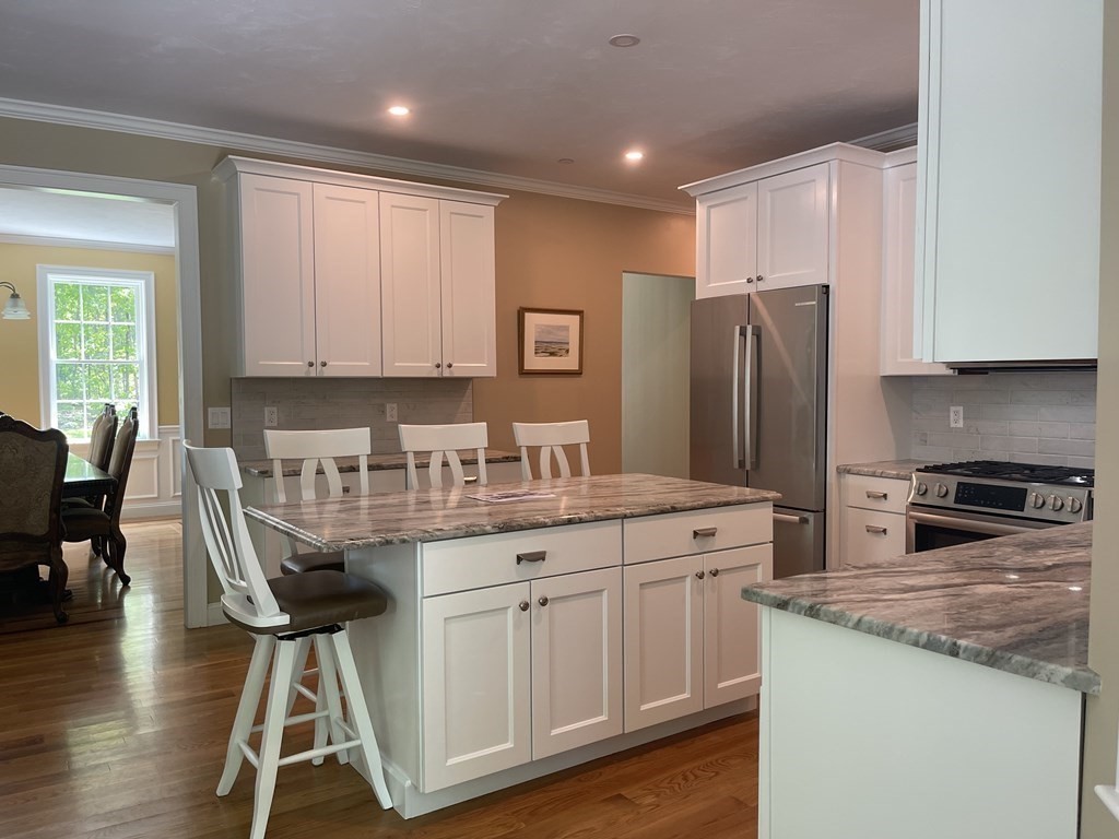 21 Gibbs Road Berlin, MA 01503 - Photo 7 of 29 a kitchen with stainless steel appliances granite countertop a stove a refrigerator a sink a dining table and chairs with wooden floor