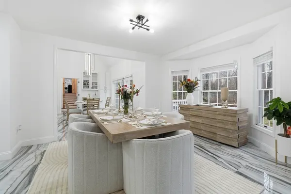 a dining hall with stainless steel appliances granite countertop a couch and chandelier