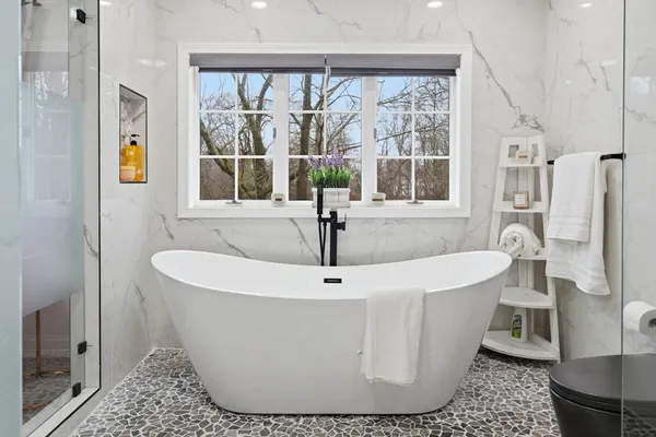 a white bath tub sitting in a bathroom next to a window