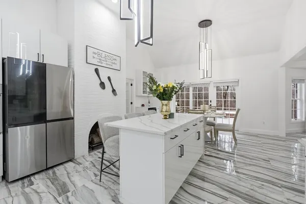 a kitchen with stainless steel appliances kitchen island a table chairs in it and wooden floors
