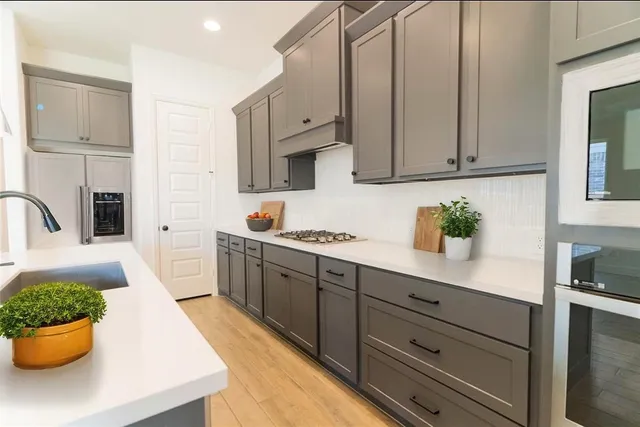 a kitchen with stainless steel appliances a white cabinets wooden floors and a sink