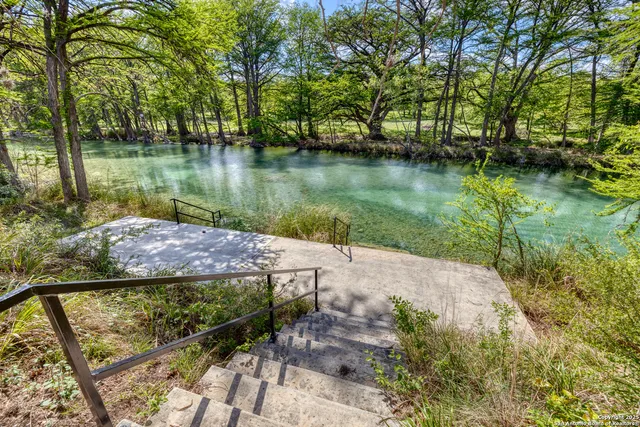 a view of a lake with a yard and large trees