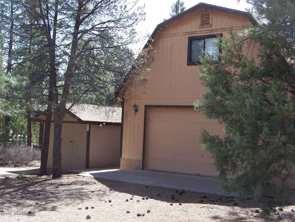 3156 Chevelon Road Overgaard, AZ 85933 - Photo 34 of 46 a front view of a house with a yard and garage