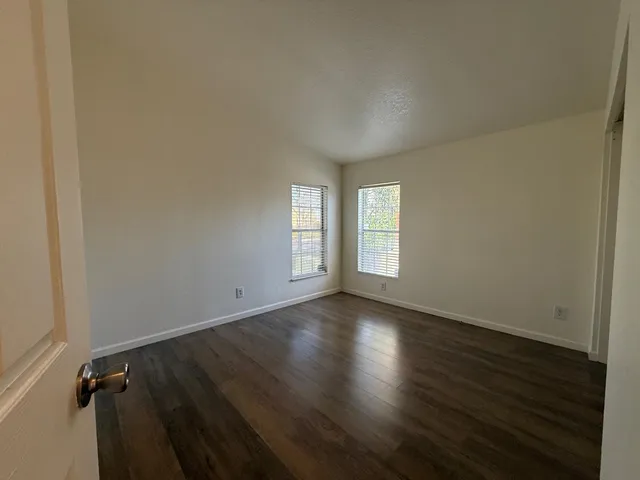 an empty room with wooden floor and windows