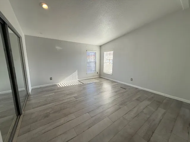 an empty room with wooden floor and windows