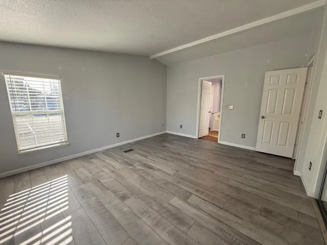 an empty room with wooden floor and windows