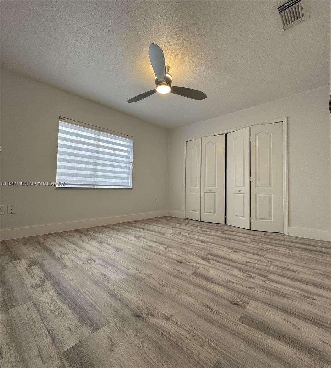 Richmond West Miami, FL 33187 - Photo 8 of 10 a view of an empty room with chandelier fan and wooden floor