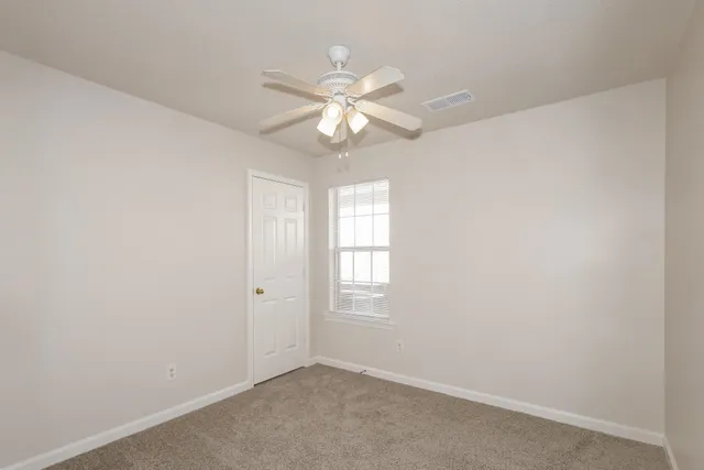 an empty room with windows and fan