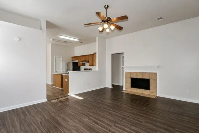 a view of an empty room with wooden floor and a fireplace