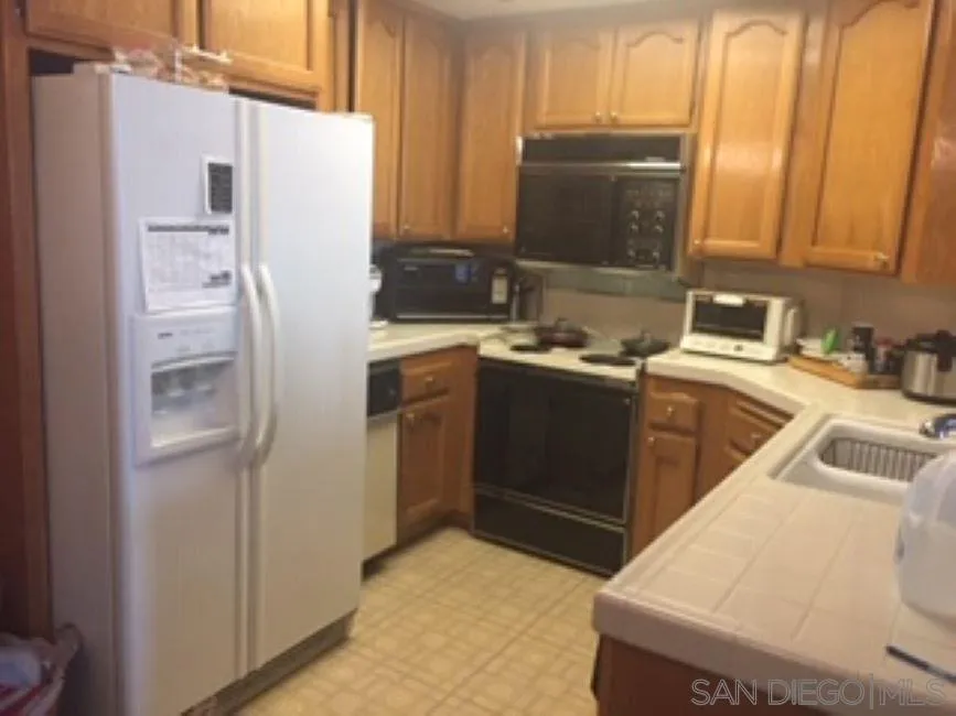 5845 Friars Road, Unit 1206 San Diego, CA 92110 - Photo 4 of 9 a kitchen with a sink a refrigerator and cabinets