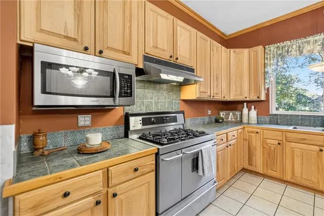 a kitchen with stainless steel appliances granite countertop a stove a sink and a microwave