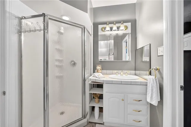 a bathroom with a granite countertop sink mirror and a shower