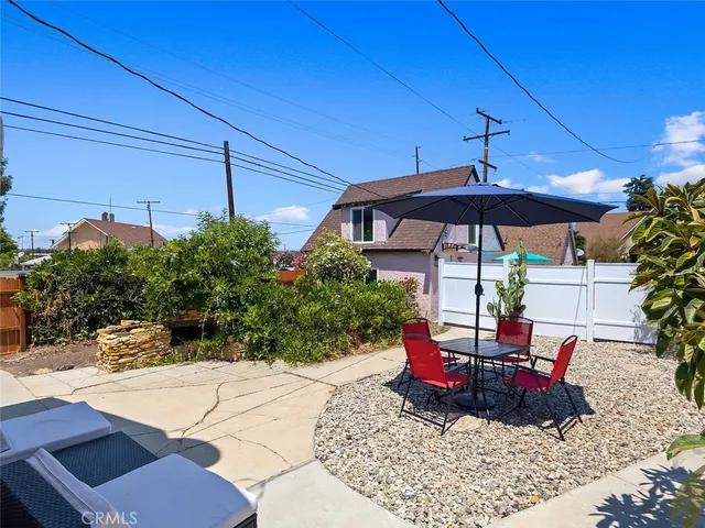 a view of a table and chairs under an umbrella in backyard of house