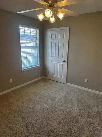 an empty room with a chandelier fan and windows