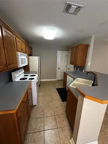 a kitchen with a sink a stove top oven a refrigerator and blue cabinets