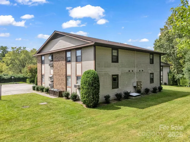 a front view of house with yard and trees in the background