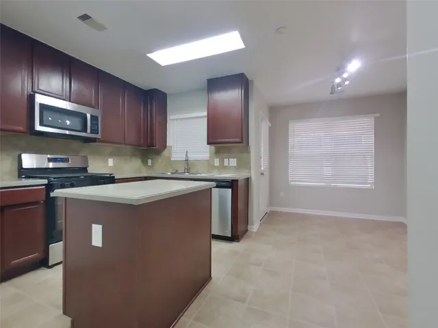 a kitchen with stainless steel appliances granite countertop a stove top oven a sink and dishwasher