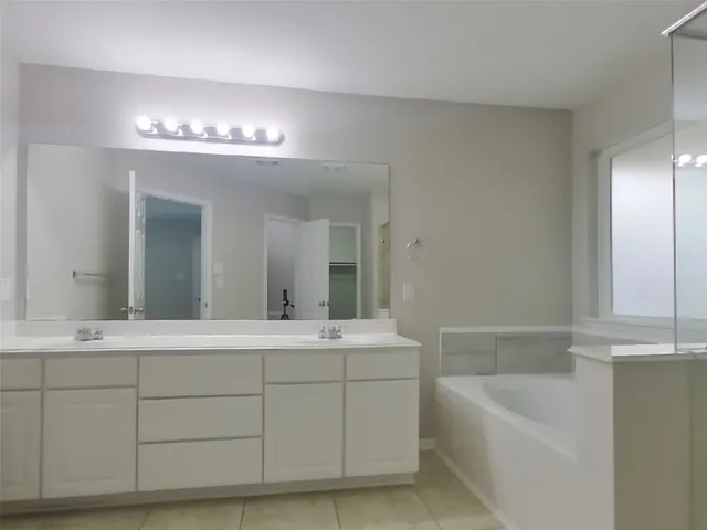 a bathroom with a bathtub a mirror a double vanity sinks and vanity