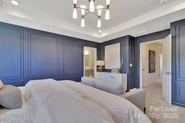 a spacious bedroom with a large bed a chandelier and a dresser