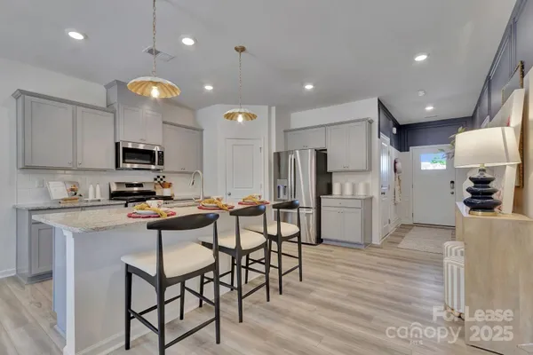 a kitchen with stainless steel appliances kitchen island granite countertop a refrigerator a stove top oven a sink and cabinets