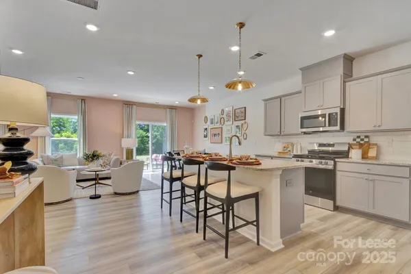a open dining room with stainless steel appliances granite countertop wooden floor a stove top oven a dining table and chairs