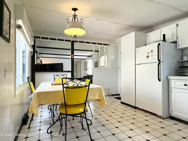 a dining room with furniture a chandelier and a refrigerator