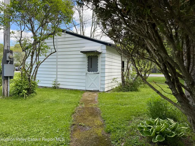 a backyard of a white house with potted plants and large trees