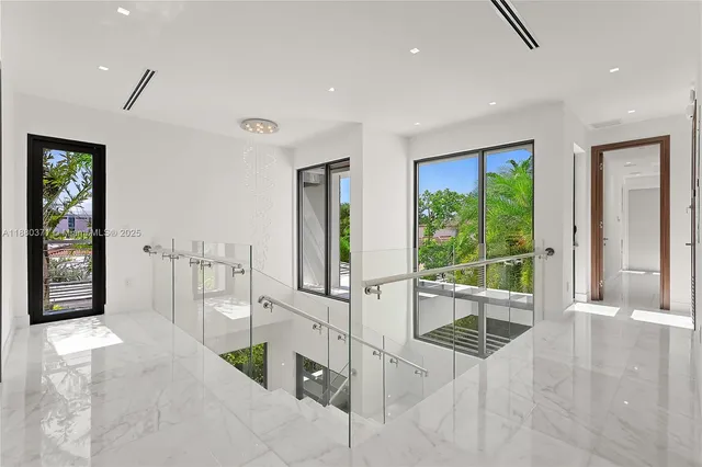 a room with lots of white furniture and large windows