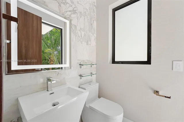 a bathroom with a sink mirror and a toilet