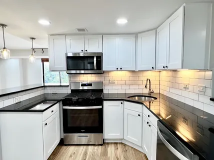 a kitchen with granite countertop a sink a stove and cabinets