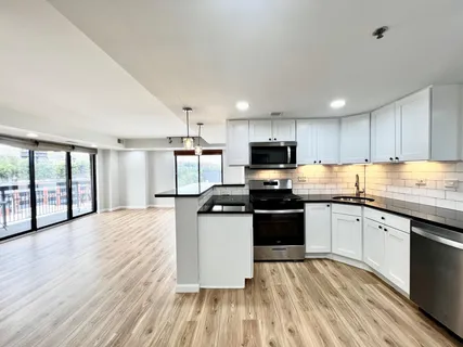 a kitchen with granite countertop a stove top oven a sink dishwasher a refrigerator and white cabinets with wooden floor