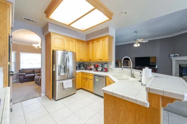 a kitchen with stainless steel appliances kitchen island granite countertop a refrigerator a stove and a sink with couches