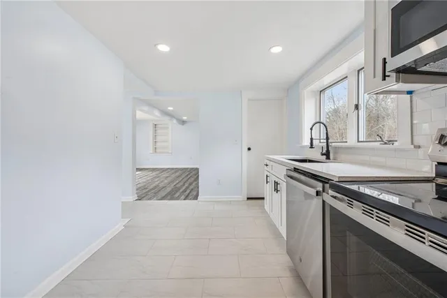 a large kitchen with granite countertop a sink and a stove top oven with wooden floor