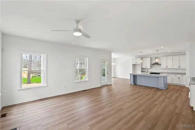 a view of kitchen with kitchen island wooden floor and stainless steel appliances