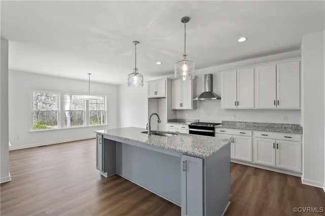 a kitchen with granite countertop a stove a sink a center island and wooden floor